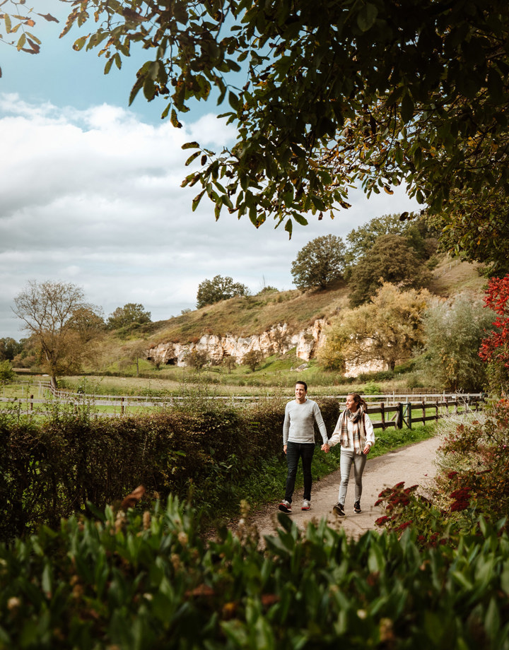 Koppel wandelt hand in hand richting de camera, langs een mergelwand rondom de Bemelerberg